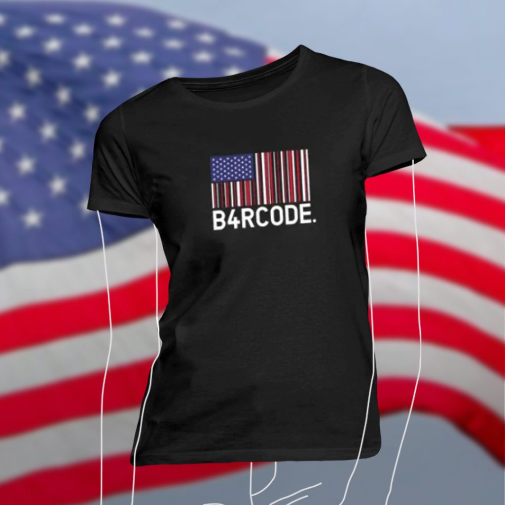 Bild eines schwarzen frauen T-Shirts mit dem B4RCODE. USA Design darauf. Im Hintergrund eine USA Flagge. Image of a black women's t-shirt featuring the B4RCODE. USA design on it. In the background, a USA flag.